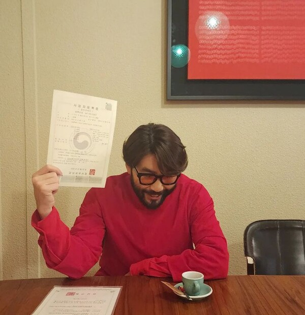 노홍철이 눈에 띄는 붉은 옷을 입고 사업자등록증과 영업신고증을 내보이고 있다. /노홍철 SNS.